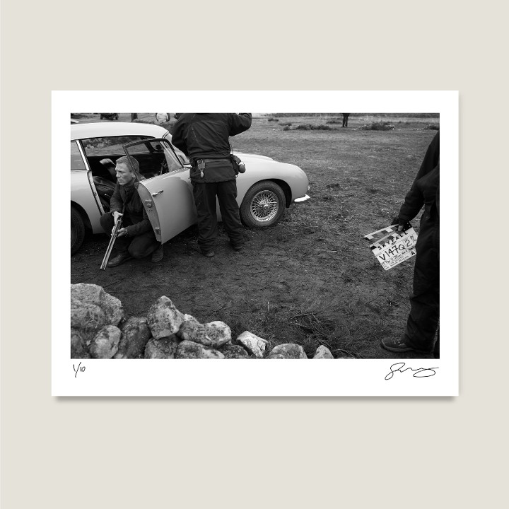 Daniel Craig and the DB5 on location at Hankley Common, Surrey. Skyfall, 2012. Archival pigment print on Hahnemühle Fine Art Baryta Satin 300gsm.

Signed Limited Edition Price increases with every sold unit.